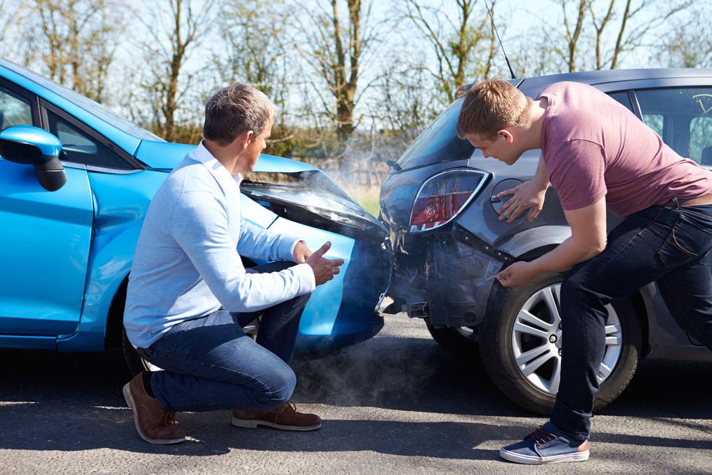 Two drivers inspect their cars after an accident