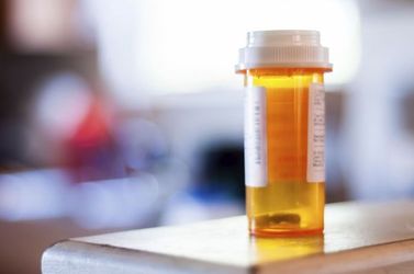 An empty pharmaceutical pill bottle sits empty on a table 